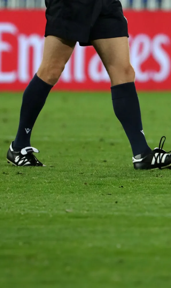 Male rugby player walking across the pitch with his socks pulled up