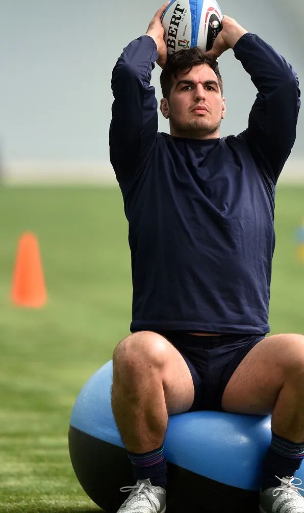 Player training with a rugby ball on a gym ball