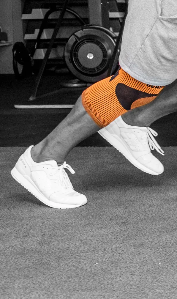 Black and white image of a man training in the gym wearing a Bearhug knee support